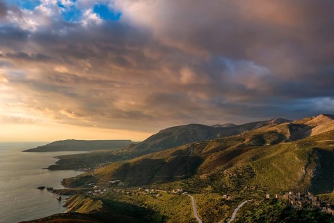 Golden hour view of the rugged hills and coastal villages of the Mani Peninsula, with winding roads