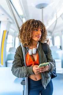 Vertical portrait of a beauty confident latin woman with curly hair and casual clothes using phone