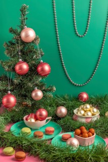 Small Christmas tree with baubles and macaroons in pink and green, surrounded by decorations