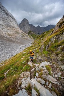 A mountaineer on a hiking trail with lush green vegetation, hiking trail to the Wolayerseehütte,