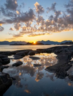 Clouds reflected in a small pond on a rocky coast, coastal landscape at sunset, Henningsvær,