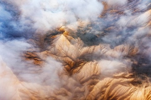 Stunning aerial view of rocky mountain peaks partially obscured by white clouds The landscape