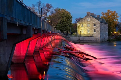 Illuminated Moulin Neuf water flow control dam and walkway over Des Mille-Iles river plus New Mill