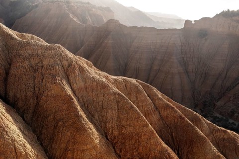 A stunning aerial view of a rugged mountain landscape with sharp ridges and soft light casting