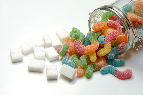 Lots of colorful jelly sweets in glass containers and sugar cubes, sugar consumption