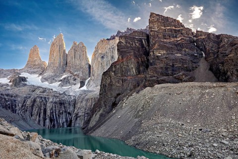 Massive rock formations and snow surround a narrow mountain lake, The rock towers of Torres del