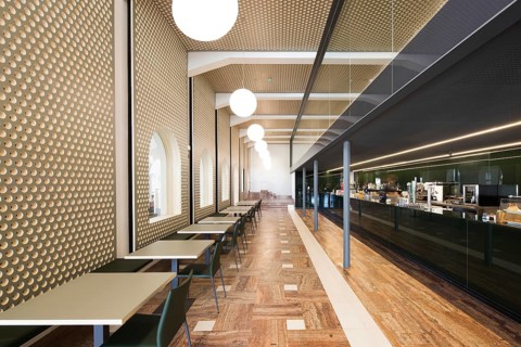 A stylish bar interior featuring geometric wall patterns, a sleek bar, and modern lighting,