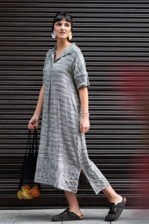 A fashionable woman walks confidently in the city while carrying a black bag with oranges and
