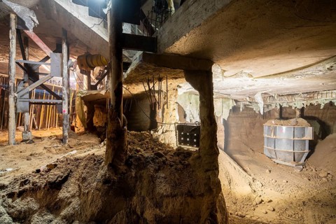 Illuminated underground construction site displaying active excavation work. The scene features