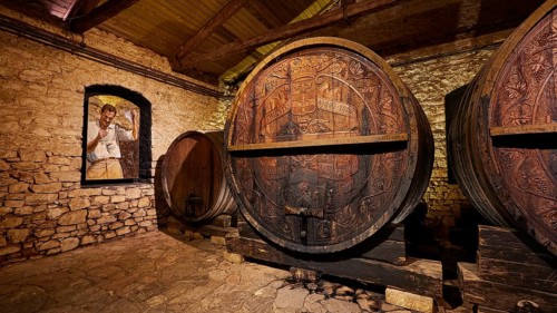 Wooden barrels in a historic wine cellar with painted wall decoration, Achaia Clauss winery,