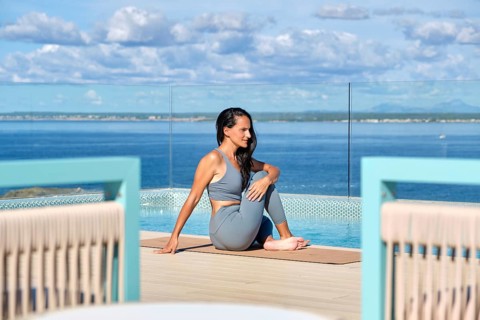 A woman practices yoga on a deck overlooking a vast ocean, enjoying a peaceful environment. The