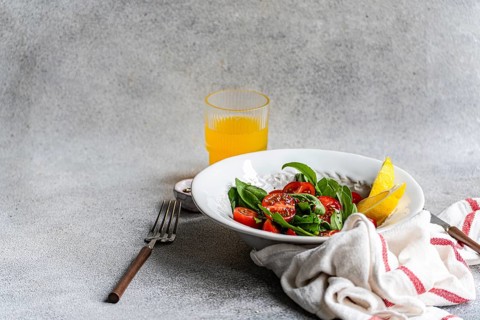 A refreshing arugula and herb salad, elegantly garnished with Himalayan salt, olive oil, cherry