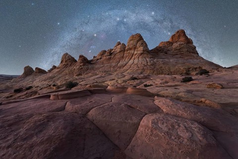 A breathtaking view of jagged rock formations under a vast, starry night sky, capturing the beauty