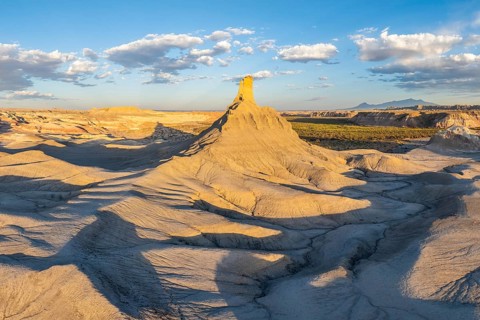 A panoramic view of dramatically eroded sandstone formations under the warm light of a setting sun