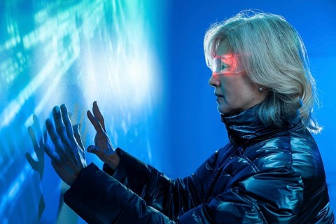 Elderly Asian woman immerses in the metaverse, exploring holographic digital interfaces. Wearing a