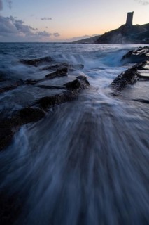 A mesmerizing sunset over the coast of Cadiz in Tarifa. Waves crash onto rocky shores as the sky