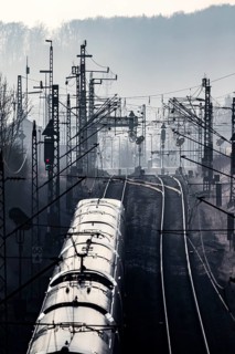 Deutsche Bahn AG tracks with ICE train against the light. Overhead line, signals and infrastructure