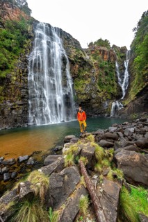 Young man standing in front of a waterfall, Lisbon Falls, long exposure, near Graskop, Mpumalanga,