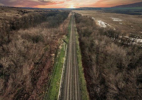 From above, a drone captures the serene landscape of a railway slicing through a barren forest in