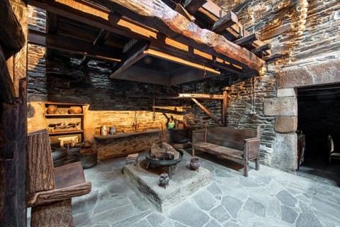 Traditional rustic kitchen inside a country house in Lugo, Spain, featuring stone walls, wooden
