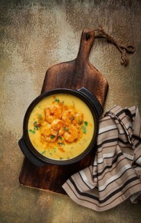 Creamy shrimp curry with spices, garnished with herbs, on a textured background, homemade, no