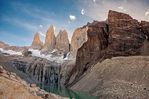 Dramatic mountain landscape with towering cliffs and a small lake in the foreground, The rock