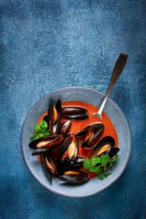 Fra Diavolo mussels, mussels in tomato sauce, Italian dish, on a blue background, homemade, no