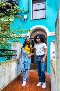 Vertical photo with copy space of a young casual african couple leaving a blue colorful house