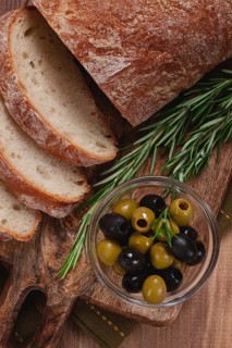 Sliced ciabatta, on a chopping board, with rosemary and olives, Italian bread, close-up, Italian