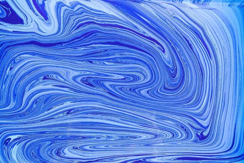 This image showcases a pattern of blue and white acrylic paint swirls resembling marble. The fluid,