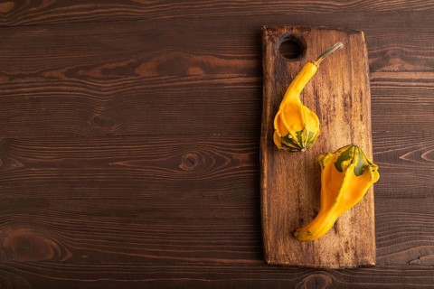 Two decorative orange Pumpkins on cutting board on brown wooden background, top view, flat lay,