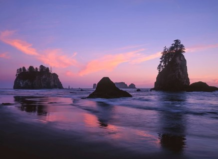 The sky glows in shades of pink and purple as the sun sets over Second Beach, with sea stacks