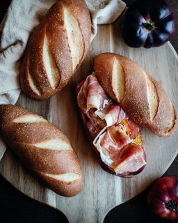Freshly baked olive oil bread topped with slices of serrano ham and ripe tomatoes on a rustic