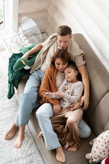 Top view image of a family of four celebrates Christmas in a warm, cozy setting. The mother,