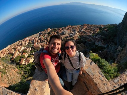 A joyful couple takes a selfie overlooking the charming town and azure sea from the heights of