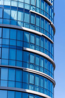 Modern architecture, highlighting a curved building with a vibrant blue glass facade against a