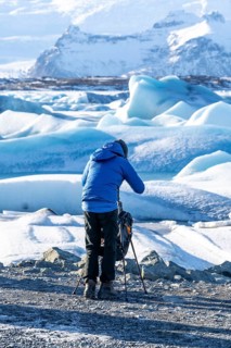 A photographer photographing the floating icebergs in the Jokulsarlon glacier lagoon in Iceland.
