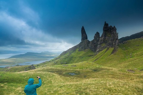 UK. Scotland. Isle of Skye. A tourist taking a picture of the Old Man of Storr during a storm