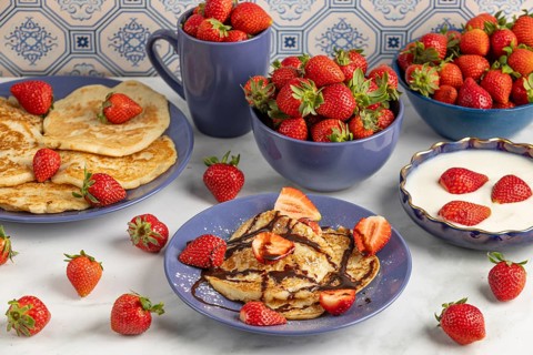 Pancakes with strawberries Chocolate syrup next to fresh strawberries and yoghurt in blue crockery