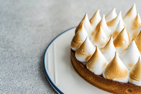Close up image of a homemade lemon cake, showcasing its golden brown peaks and buttery crust. The