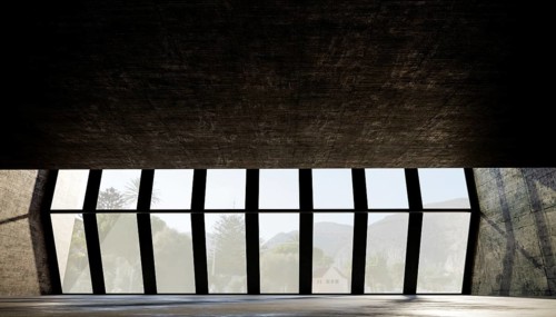 Large geometric windows frame a scenic view, with natural light illuminating the textured concrete