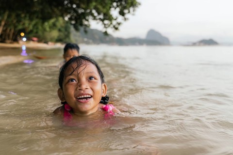 Two children enjoy swimming in the warm, shallow waters of a beach in the Philippines, surrounded