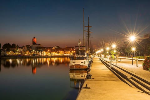 Sailing boats in the port of Wolgast at dusk, blue hour, in the back the old town with St. Peter's