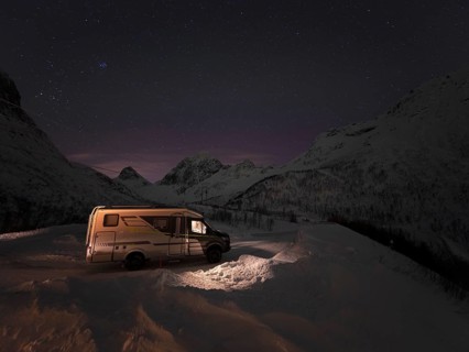 Winter motorhome under a starry sky on the island of Senja in a serpentine, Troms, Norway