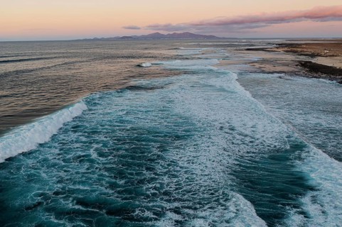 A serene view of Popcorn Beach as twilight settles, showcasing gentle waves rolling onto the