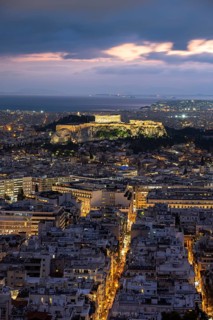 View over the sea of houses of Athens, illuminated Parthenon temple on the Acropolis, dramatic