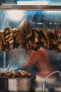 Unrecognizable person preparing traditional street food in Hong Kong, with hanging dried items and
