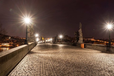 Illuminated at night, Charles Bridge in Prague showcases statues and cobblestones under glowing