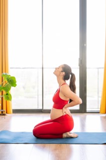 A pregnant woman practices yoga in a serene setting, embracing wellness and relaxation. She kneels