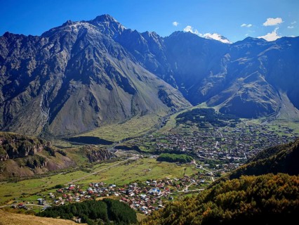 Panorama of a valley with a city and dramatic mountain ranges, Stepantsminda, Caucasus, Georgia